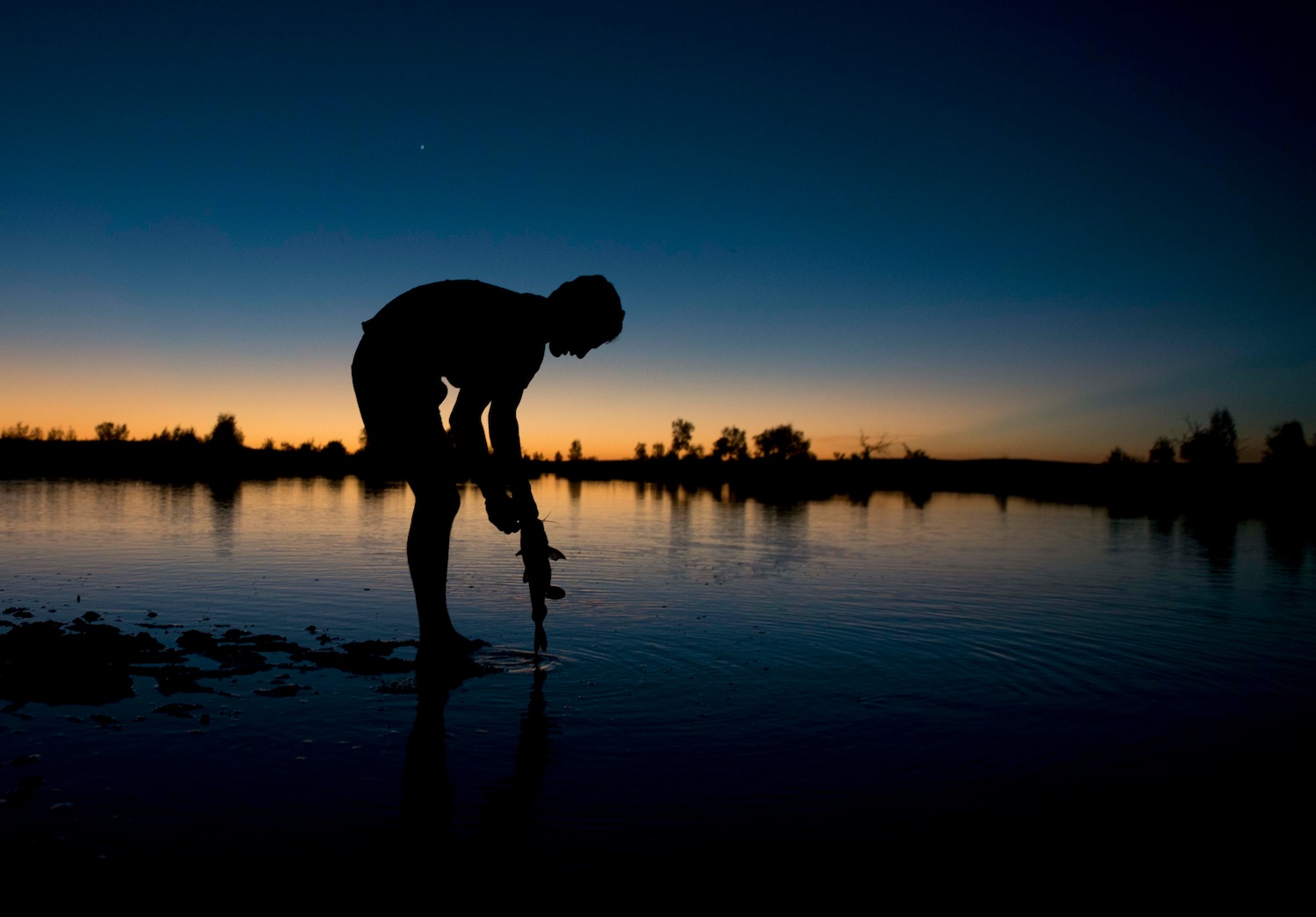 Our local guide Naverone Stalerno fishes at sunset in the Outback of Australia.